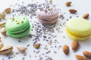 yellow, green and purple macaron cakes or macaroon on white background, sweet and colorful dessert, above, almond cookies, pastel color, vintage card, lavender, pistachios and almond on the background