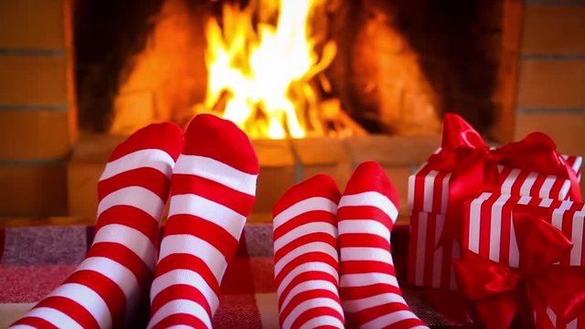 Family in Christmas socks near fireplace. Mother and baby having fun together. People relaxing at home. Winter holiday Xmas and New Year concept