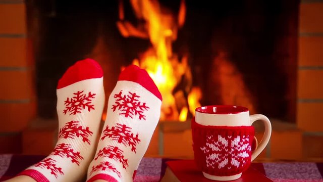 Woman in Christmas socks near fireplace. Girl relaxing at home. Winter holiday Xmas and New Year concept