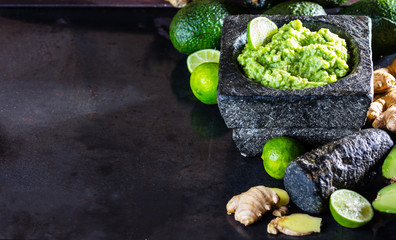 Latinamerican mexican guacamole with avocado ginger, lime in stone mortar
