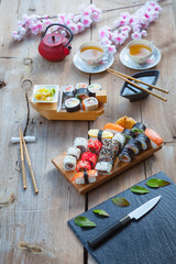 Fototapeta na wymiar A variety of sushi and green tea set on rustic wooden table.