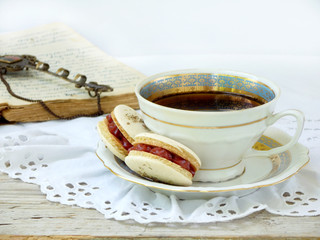 romantic breakfast with cup of espresso coffee and French macaroons dessert on light wooden background