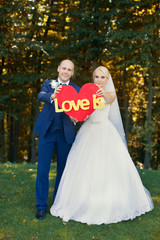 Newlyweds are holding a red heart