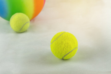 tennis balls and rainbow colored plastic ball on white ground