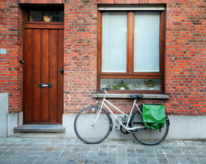 Fototapeta na wymiar Piece of typical european old street - pebble pavement, wooden door of apartment, mail box and bicycle. Selective focus.