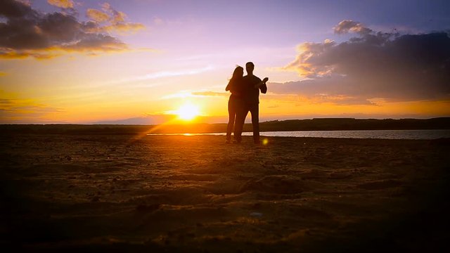 loving man and woman dancing in the sunset under the blue sky on the lake