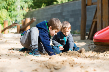 Two young boys playing in a sandpit