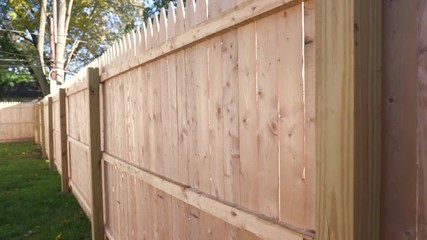 Lowering Down the Side of a New Fence. shot moves down the side of a newly installed fence in a backyard
