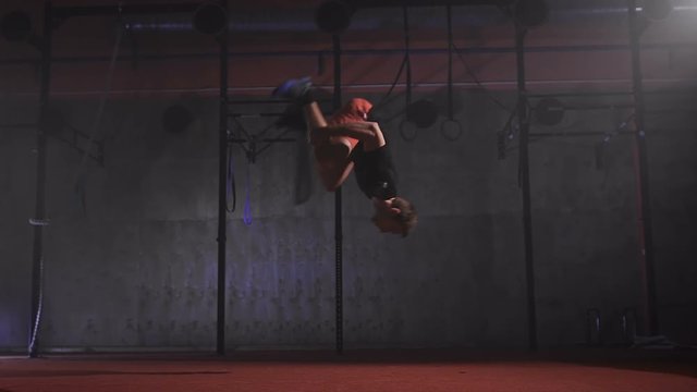 Strong muscular man making crossfit back and front flip burpees at the gym in slow motion.
