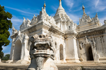 Fototapeta na wymiar White Pagoda at Inwa ancient city with lions guardian statues. Amazing architecture of old Buddhist Temples. Myanmar (Burma) travel landscapes and destinations