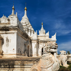 Fototapeta na wymiar White Pagoda at Inwa ancient city with lions guardian statues. Amazing architecture of old Buddhist Temples. Myanmar (Burma) travel landscapes and destinations
