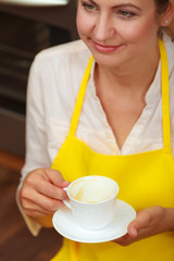 Mature woman with cup of coffee in kitchen.