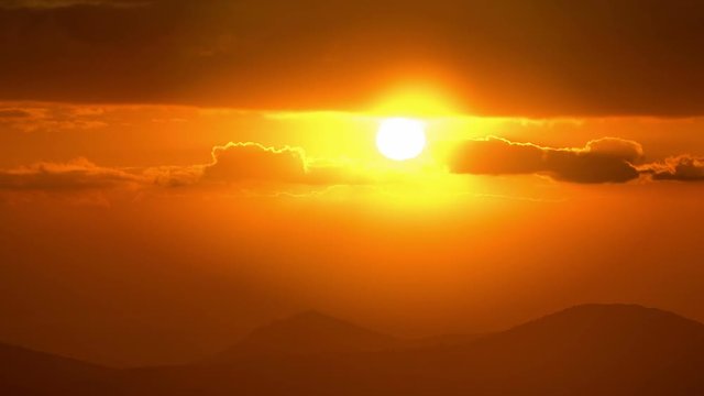 Vivid sunrise over silhouetted hills,bright red sun, timelapse.