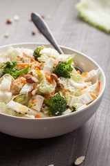 Asian Napa cabbage salad with organic broccoli, almonds, chicken, and a rice vinaigrette side view on dark wood background
