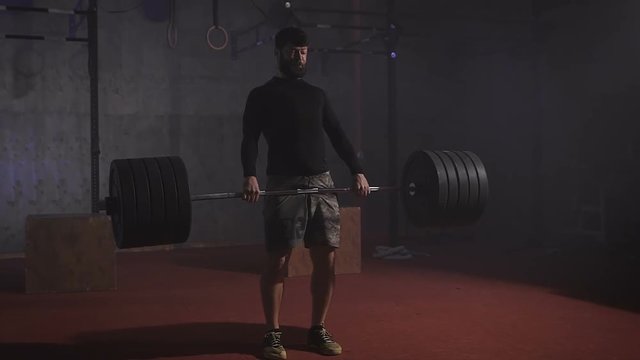 Strong athlete raises the bar with a very large weight.