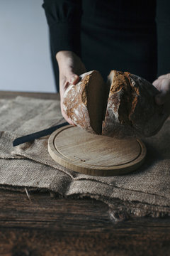 Woman slicing freshly baked rye bread on a rustic wooden table