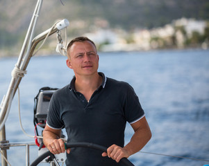 Young man at the helm of a sailing yacht.