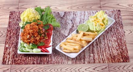 Spicy fried chicken salad (Yum Kai Zap in Thai) served mixed vegetables salad and french fires.