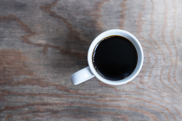Cup of coffee on wooden table, top view