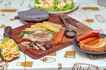 Pork steak and mixed vegetables on butcher served with side dish as parmesan cheese bread ,sausage ,shiitake fresh mushroom soup and salad,Home made.