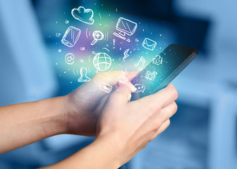 Hand holding smartphone with media icons