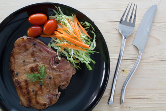 steak with salad and tomatoes on wood background