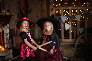 Obraz premium Two little girls laughing witch on a broomstick. childhood Hallo