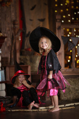 Naklejka premium funny children girls in witch costume play for Halloween dark