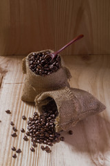 Coffee beans and spoon  in a bag on wooden background