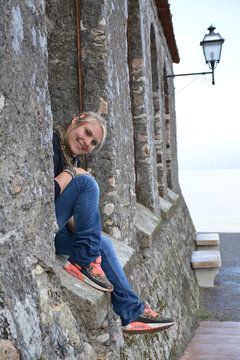 Attraktive l&auml;chelnde Frau sitzt in der Fensterlaibung vor der Laterne
