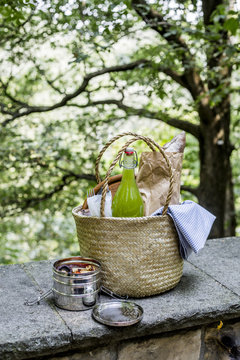 Picnic basket on wall with lemonade bottle, lunch box, artisan b