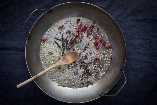 Whole spices prepared for roasting in a pan before dark backgrou