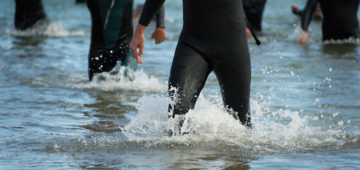 Triathletes group,splash of water while triathletes running in sea