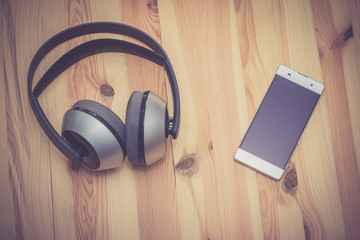 Smartphone und Kopfhörer auf Holzuntergrund