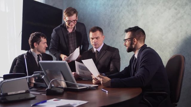 business people having a meeting conference talking about future success of the company. modern city office interior, group of four business man working on laptop at meeting together in room