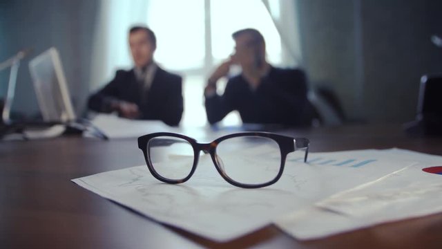 
financial chart near dollars seen by unfocused glasses ( colleagues meeting to discuss their future financial 

plans only silhouettes being viewed )