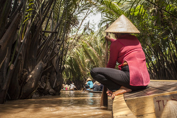 Unidentified vietnamese man rowing in a wood boat in  the Mekong delta. Boat trips in the Mekong...