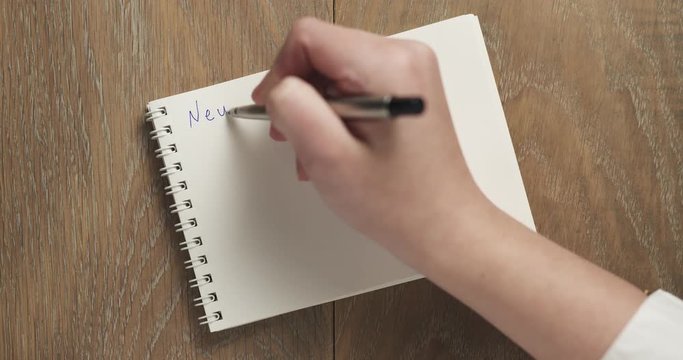 female teen writes new year resolution on blank notepad