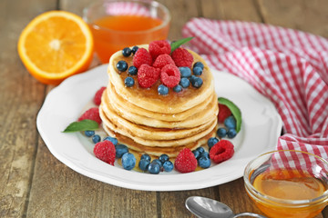 White plate full of tasty pancakes with berries and honey
