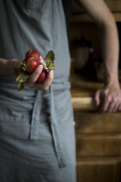 Man with kitchen apron leaning on kitchen cabinet and holding ap
