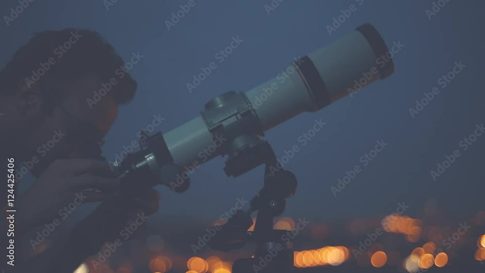 Wall mural man looking at the stars with telescope with de-focused city lights.
