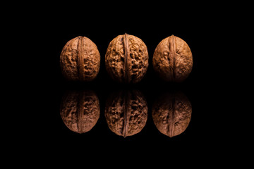 Three whole walnuts isolated on black background