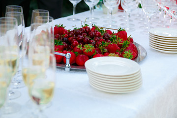 Reception table. Glasses of wine, champagne, plates and berries on the white tablecloth. Catering business.
