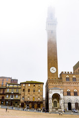 Obraz premium Downtown Siena in Tuscany with Town Hall Tower in fog