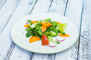 Fresh salad with summer vegetables on the wooden table. Shallow depth of field.