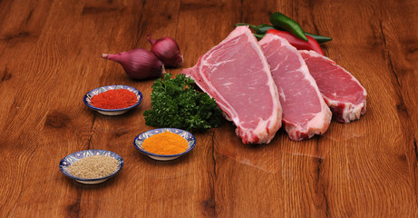 raw meat with herbs and lettuce and onions with pepper on the varnished board