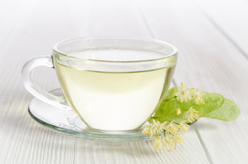 Glass cup of tea with linden on white wooden table