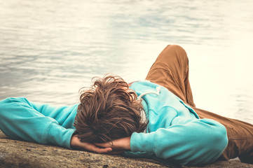 Young Man laying relaxing outdoor with lake on background Lifestyle Travel concept