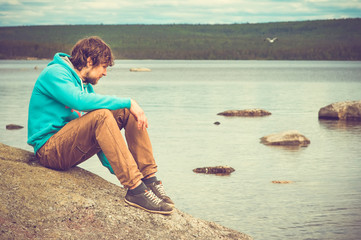 Young Man relaxing outdoor on mountain with lake on background Summer vacations and Lifestyle hiking concept