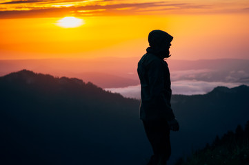 Man Traveler silhouette standing alone outdoor with sunset mountains on background Travel Lifestyle and survival concept